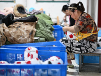 Workers make footballs by hand for export to overseas markets such as Japan at a sports goods factory in Suqian, Jiangsu province, China, on...