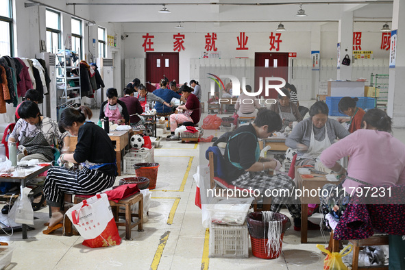 Workers make footballs by hand for export to overseas markets such as Japan at a sports goods factory in Suqian, Jiangsu province, China, on...