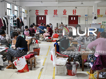 Workers make footballs by hand for export to overseas markets such as Japan at a sports goods factory in Suqian, Jiangsu province, China, on...