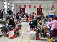 Workers make footballs by hand for export to overseas markets such as Japan at a sports goods factory in Suqian, Jiangsu province, China, on...