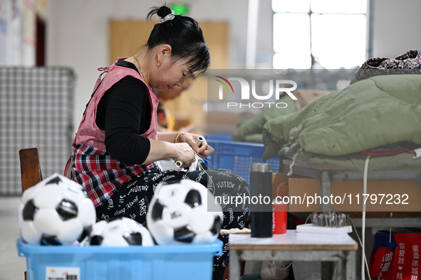 Workers make footballs by hand for export to overseas markets such as Japan at a sports goods factory in Suqian, Jiangsu province, China, on...