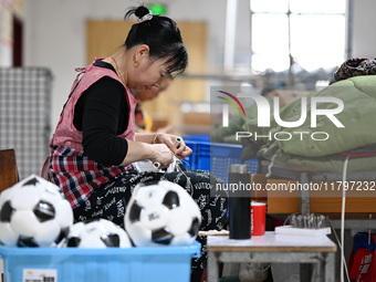 Workers make footballs by hand for export to overseas markets such as Japan at a sports goods factory in Suqian, Jiangsu province, China, on...