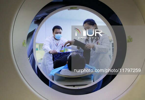 A medical worker performs a CT examination on a patient in Handan, Hebei province, China, on January 1, 2022. 