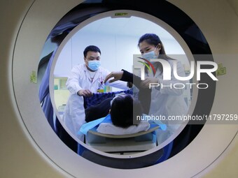 A medical worker performs a CT examination on a patient in Handan, Hebei province, China, on January 1, 2022. (