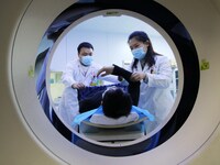 A medical worker performs a CT examination on a patient in Handan, Hebei province, China, on January 1, 2022. (