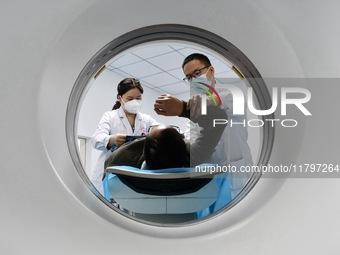 A medical worker performs a CT examination on a patient in Handan, Hebei province, China, on January 1, 2022. (