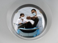 A medical worker performs a CT examination on a patient in Handan, Hebei province, China, on January 1, 2022. (