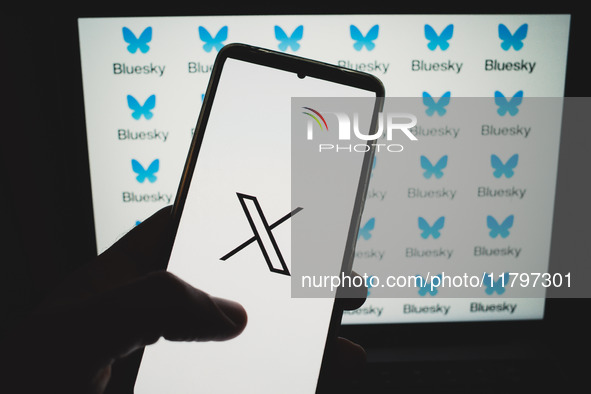 The X (formerly Twitter) logo appears on a smartphone screen, and Bluesky logos appear in the background on a computer screen in this photo...