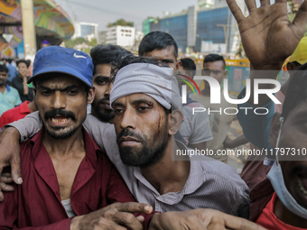 An injured automatic three-wheel driver leans on his fellow driver after a clash with the Bangladesh Armed Forces in Dhaka, Bangladesh, on N...