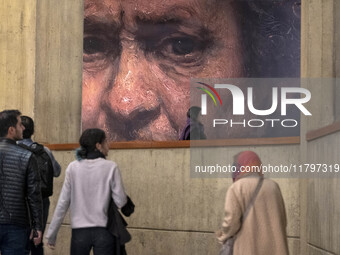 Young Iranian people walk under a copy of a detail of a self-portrait by Rembrandt (1659), the Irish painter and printmaker, while visiting...