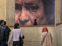 Young Iranian people walk under a copy of a detail of a self-portrait by Rembrandt (1659), the Irish painter and printmaker, while visiting...