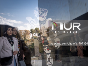 Iranian women walk past ''Cherche Aubaine'' from the series ''Deputation'' by Jean Dubuffet, the French painter and sculptor, while visiting...