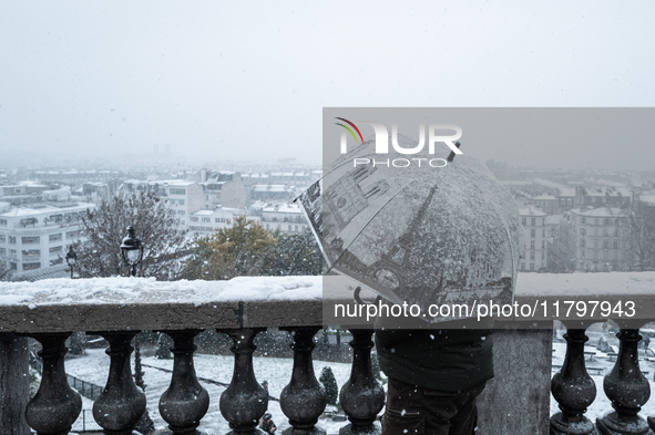 A tourist watches the heavy snowfall as Paris is placed under the second highest weather warning by the French national weather service for...