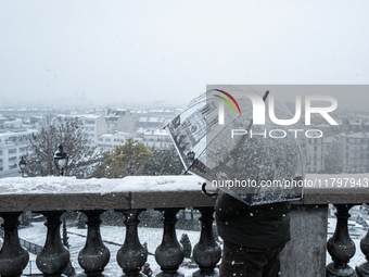 A tourist watches the heavy snowfall as Paris is placed under the second highest weather warning by the French national weather service for...