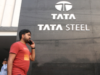 A man talks on a mobile phone in front of a Tata Steel logo in Kolkata, India, on November 21, 2024. Tata Steel's last traded price is 140.2...