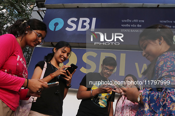 An Indian onlooker checks her mobile phone while watching share prices in front of a branch of State Bank of India Wealth Management in Kolk...