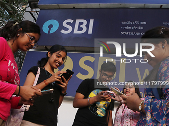 An Indian onlooker checks her mobile phone while watching share prices in front of a branch of State Bank of India Wealth Management in Kolk...