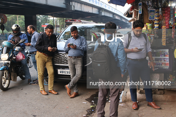 An Indian onlooker checks his mobile phone while watching share prices in Kolkata, India, on November 21, 2024. 