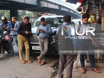 An Indian onlooker checks his mobile phone while watching share prices in Kolkata, India, on November 21, 2024. (