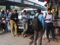 An Indian onlooker checks his mobile phone while watching share prices in Kolkata, India, on November 21, 2024. (