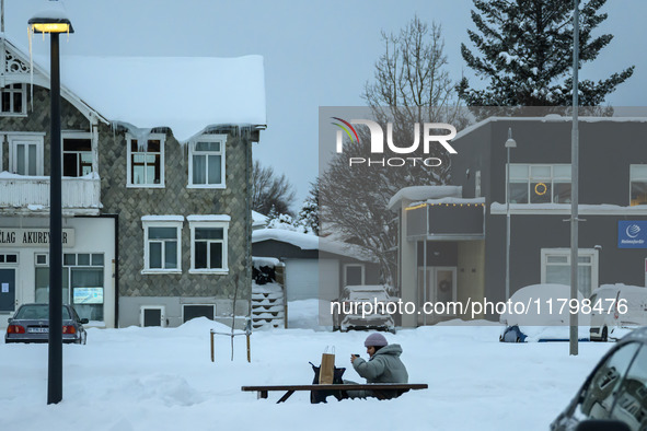 A person sits on a bench on one of the streets in Akureyri, Iceland, on November 20, 2024. 