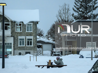 A person sits on a bench on one of the streets in Akureyri, Iceland, on November 20, 2024. (