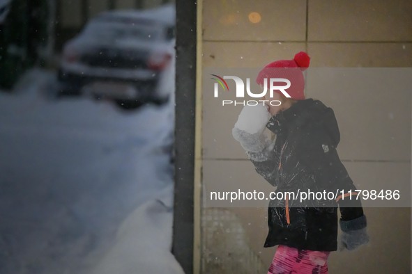 A child eats snow during a walk along a street in Akureyri, Iceland, on November 20, 2024. 