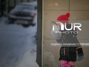 A child eats snow during a walk along a street in Akureyri, Iceland, on November 20, 2024. (