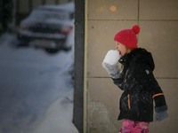 A child eats snow during a walk along a street in Akureyri, Iceland, on November 20, 2024. (