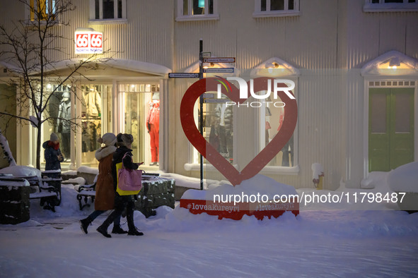 Several people walk down a street in the town of Akureyri, Iceland, on November 19, 2024. 