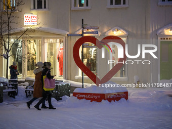 Several people walk down a street in the town of Akureyri, Iceland, on November 19, 2024. (