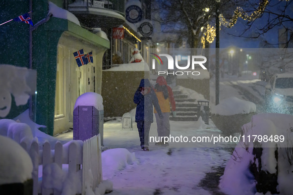 Two people walk down a street in Akureyri, Iceland, on November 19, 2024. 