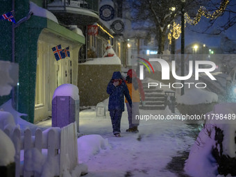 Two people walk down a street in Akureyri, Iceland, on November 19, 2024. (