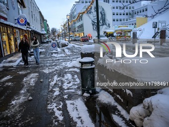 Two people walk down a street in Akureyri, Iceland, on November 19, 2024. (