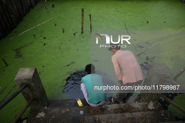 Relatives perform rituals in a polluted pond for a dead body before cremation in a furnace inside a crematorium in the Baruipur Panchayat ar...