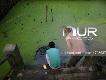 Relatives perform rituals in a polluted pond for a dead body before cremation in a furnace inside a crematorium in the Baruipur Panchayat ar...