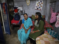 Tumpa Das, age 29, gestures with her mother inside her house during the cremation of a dead body in a furnace at a crematorium in the Baruip...