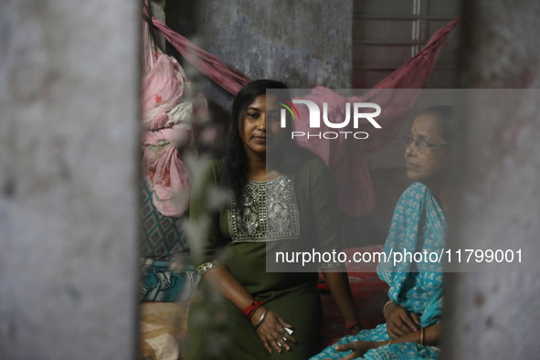 A mirror reflects Tumpa Das, age 29, as she gestures with her mother inside her house during the cremation of a dead body in a furnace at a...