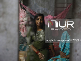 A mirror reflects Tumpa Das, age 29, as she gestures with her mother inside her house during the cremation of a dead body in a furnace at a...