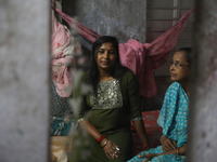 A mirror reflects Tumpa Das, age 29, as she gestures with her mother inside her house during the cremation of a dead body in a furnace at a...