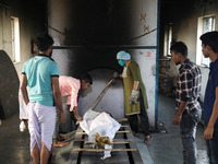 Tumpa Das, age 29, prepares a dead body for cremation in a furnace inside a crematorium in the Baruipur Panchayat area in South 24-Pargana d...