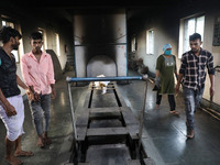 Tumpa Das, age 29, prepares a dead body for cremation in a furnace inside a crematorium in the Baruipur Panchayat area in South 24-Pargana d...