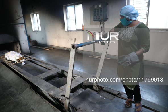 Tumpa Das, age 29, prepares a dead body for cremation in a furnace inside a crematorium in the Baruipur Panchayat area in South 24-Pargana d...