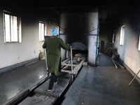 Tumpa Das, age 29, prepares a dead body for cremation in a furnace inside a crematorium in the Baruipur Panchayat area in South 24-Pargana d...