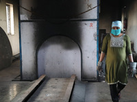 Tumpa Das, age 29, prepares a dead body for cremation in a furnace inside a crematorium in the Baruipur Panchayat area in South 24-Pargana d...