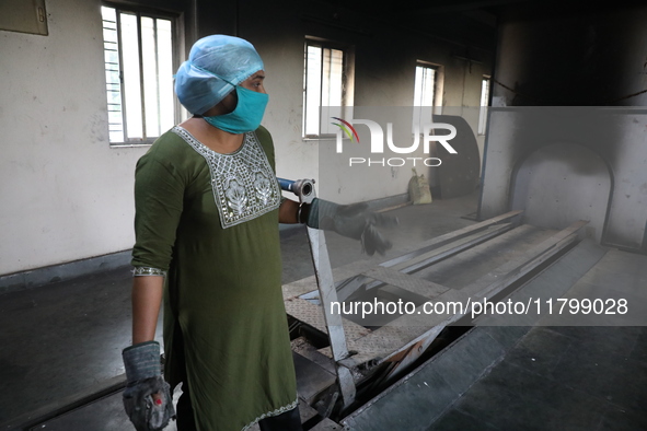 Tumpa Das, age 29, prepares a dead body for cremation in a furnace inside a crematorium in the Baruipur Panchayat area in South 24-Pargana d...