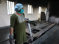 Tumpa Das, age 29, prepares a dead body for cremation in a furnace inside a crematorium in the Baruipur Panchayat area in South 24-Pargana d...