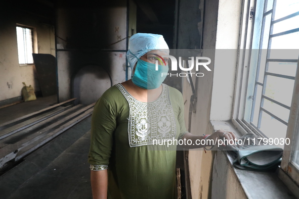 Tumpa Das, age 29, looks outside during the cremation of a dead body in a furnace inside a crematorium at Baruipur Panchayat area in South 2...