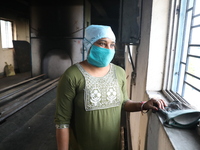 Tumpa Das, age 29, looks outside during the cremation of a dead body in a furnace inside a crematorium at Baruipur Panchayat area in South 2...