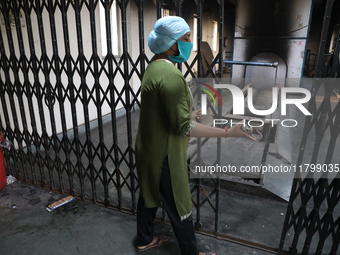 Tumpa Das, age 29, closes the gate during the cremation of a dead body in a furnace inside a crematorium at Baruipur Panchayat area in South...